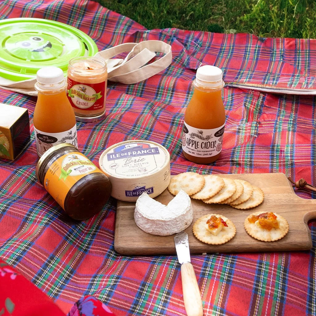 Rollicking Buckaroo medium pepper jam next to brie cheese and some crackers on top of a wood cutting board