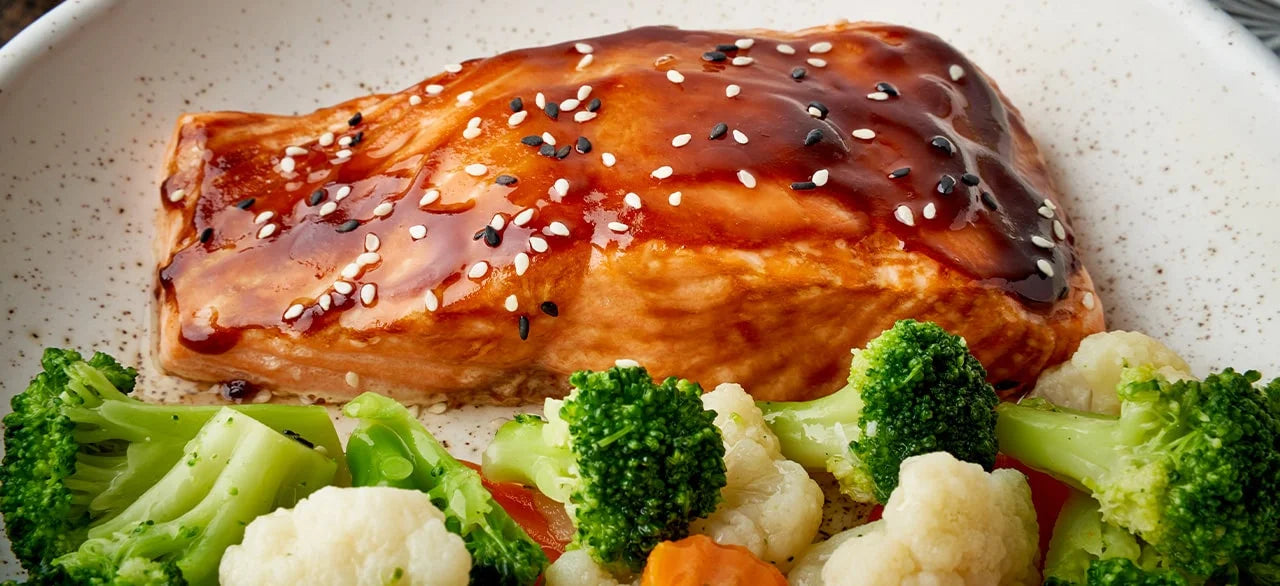 pepper jam glazed salmon on a plate next to broccoli