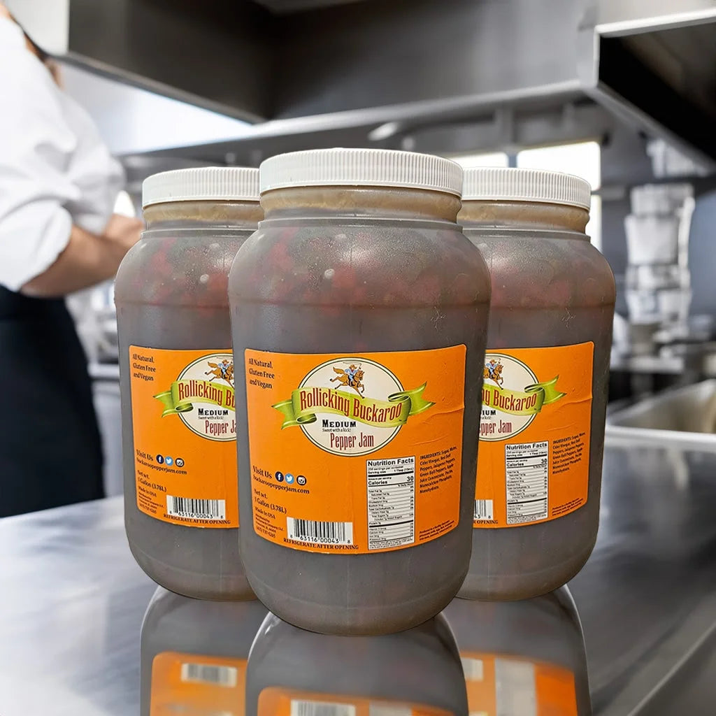 Gallon bottles of Rollicking Buckaroo Medium Pepper Jam on a restaurants stainless steel counter top