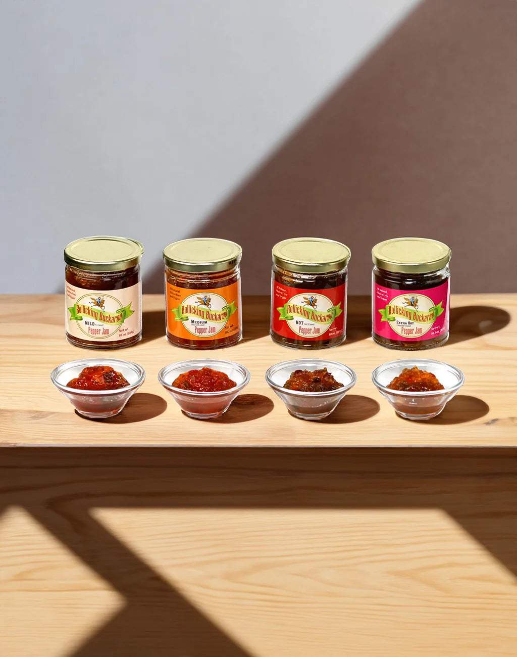 All 4 Rollicking Buckaroo Pepper Jams lined up next to each other on a wooden bar with a bowl of their pepper jam in front of the jars